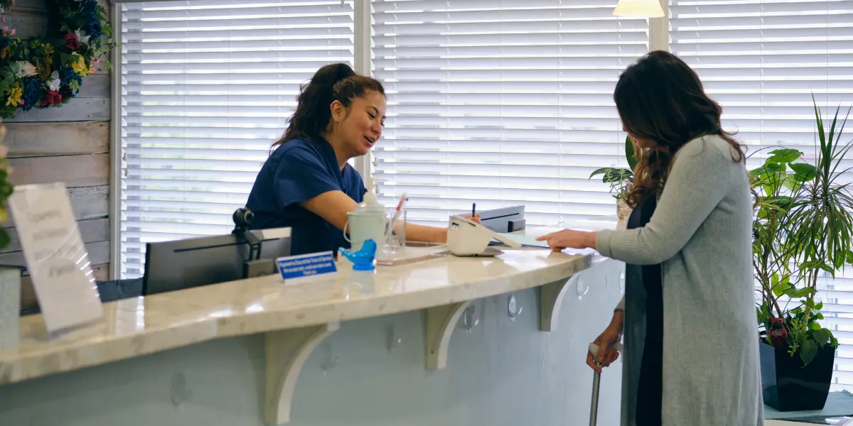 Woman in healthcare handing printed papers to a patient