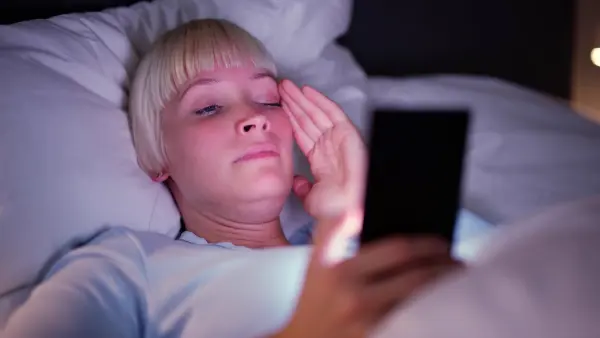Woman being woken up from sleep by using her cell phone for business